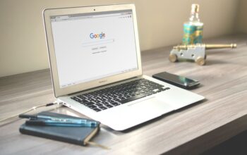 A laptop on a desk displaying the Google search page