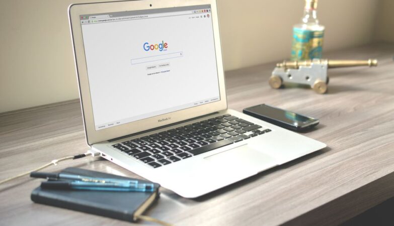 A laptop on a desk displaying the Google search page