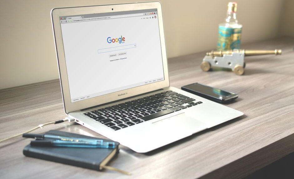 A laptop on a desk displaying the Google search page