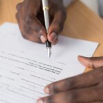 A hand signing a contract with a fountain pen