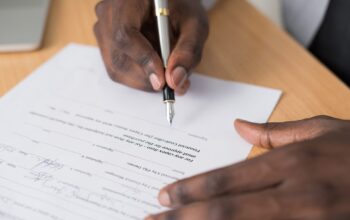 A hand signing a contract with a fountain pen