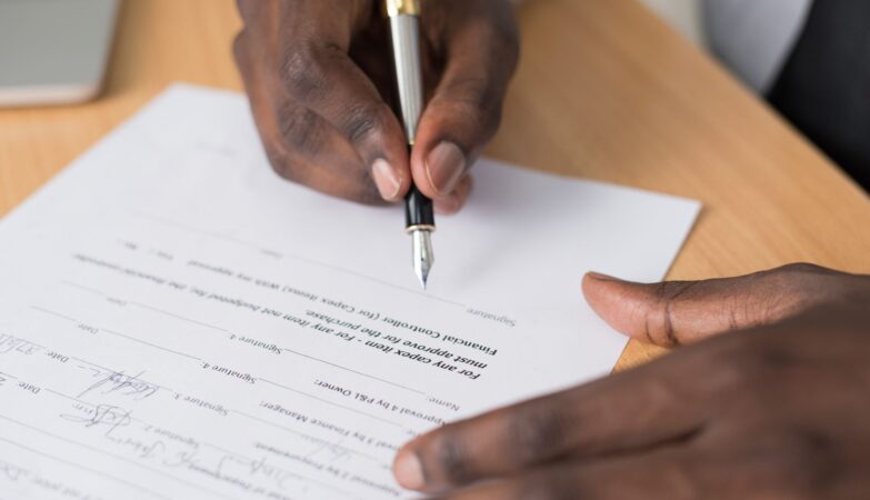 A hand signing a contract with a fountain pen
