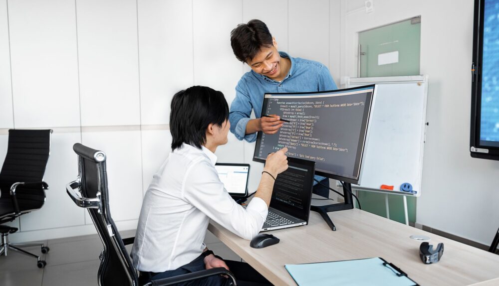 Engineers reviewing code on a monitor: So You Want to Plug In a Public-Record API? Check These Things First
