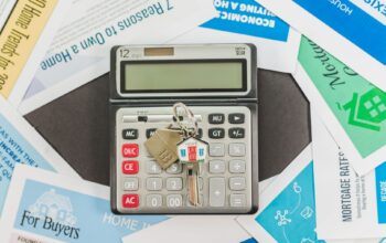 Calculator with keys and real estate documents symbolizes home buying finances.