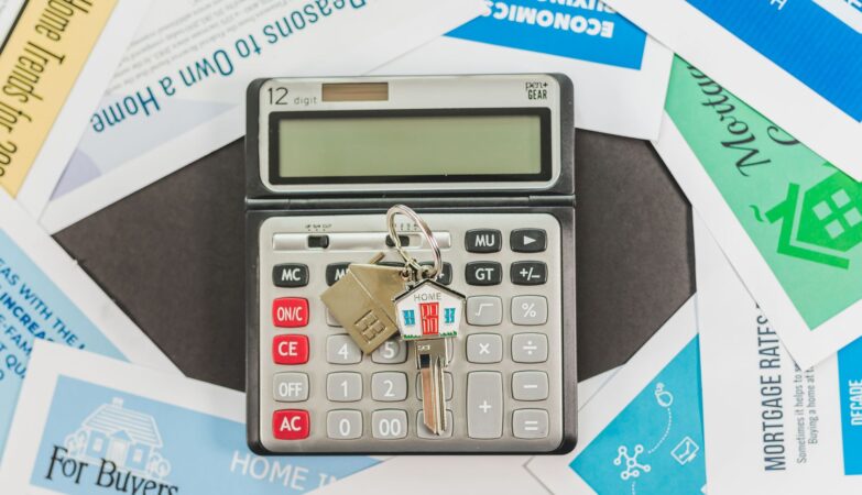 Calculator with keys and real estate documents symbolizes home buying finances.