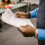 Teacher reviewing marked exam papers in a classroom