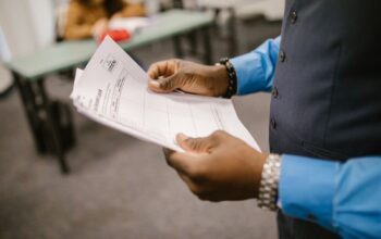 Teacher reviewing marked exam papers in a classroom