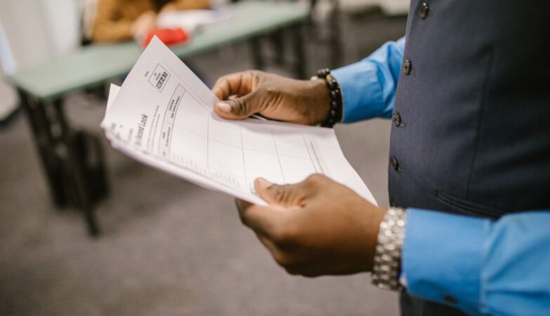 Teacher reviewing marked exam papers in a classroom