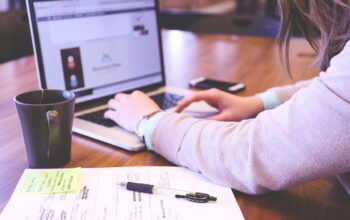 Business owner typing on a laptop beside notes and a coffee mug