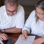 Early pension withdrawals made in haste often cause problems down the line: an older couple going through pension and retirement paperwork together at home