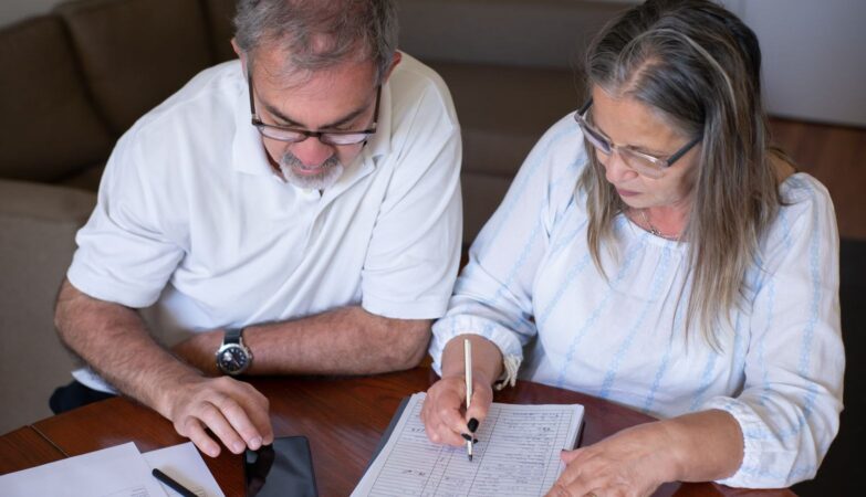 Early pension withdrawals made in haste often cause problems down the line: an older couple going through pension and retirement paperwork together at home