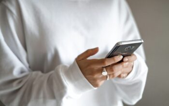How households can swap impulse spending for a planned budget and repayments: a person in a white jumper checking their household budget on a mobile phone