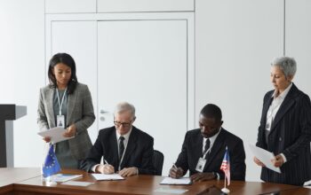 Business leaders sign an agreement at a conference table flanked by EU and US flags, illustrating practical Strategies Every Company Needs for International Business Disputes
